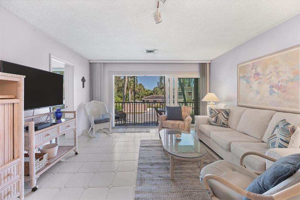 A living room features tile floors, a sofa, a glass coffee table, and a balcony view — 500 S WASHINGTON DRIVE UNIT 5B, SARASOTA, FL