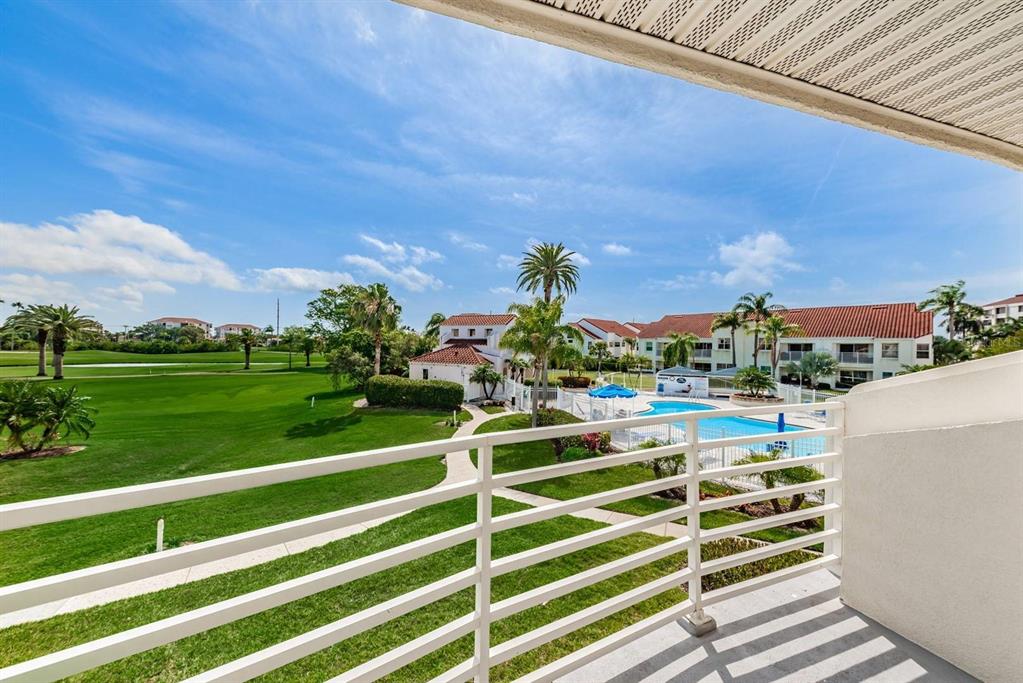 A balcony overlooks a green lawn, a swimming pool, and multi-story residential buildings — 6059 BAHIA DEL MAR BOULEVARD UNIT 241, ST PETERSBURG, FL