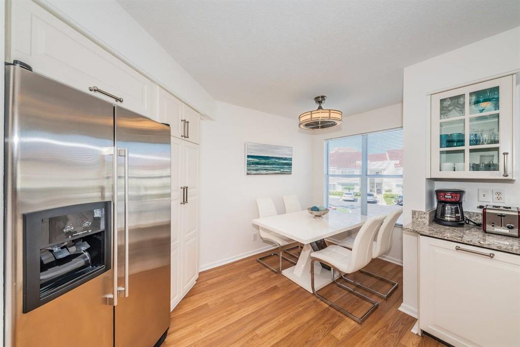 A dining area with a white table, four chairs, stainless refrigerator, and wood-look flooring — 6059 BAHIA DEL MAR BOULEVARD UNIT 241, ST PETERSBURG, FL