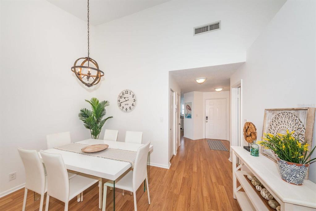 A dining area with a white table, four chairs, a globe chandelier, and wood flooring — 6059 BAHIA DEL MAR BOULEVARD UNIT 241, ST PETERSBURG, FL