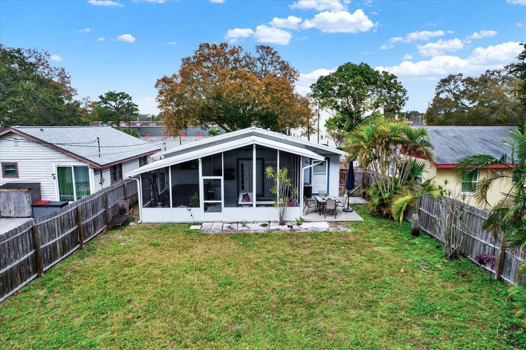A backyard view of a house with a screened-in porch and a wooden fence — 4432 73RD AVENUE N, PINELLAS PARK, FL