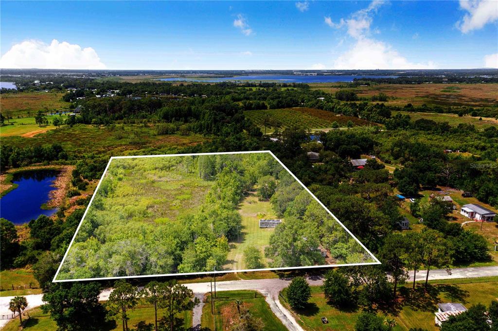 An aerial view shows a large, wooded plot of land with a small house — 6873 WILBAR LANE, HAINES CITY, FL