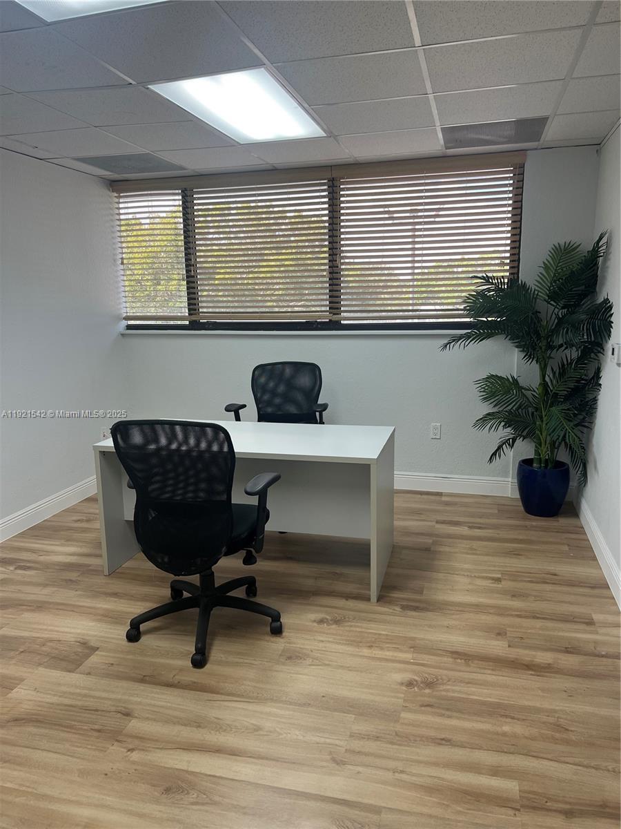 An office space features a white desk, two black chairs, and a potted plant — 351 S Cypress Rd, Pompano Beach FL 33060, POMPANO BEACH, FL