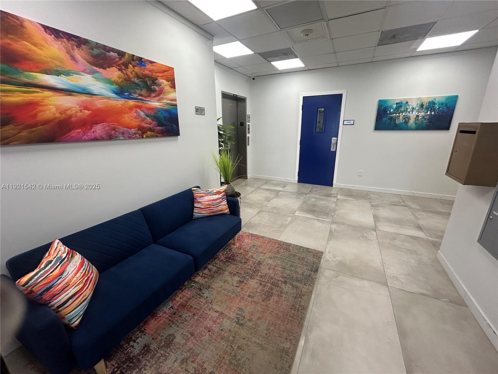 A waiting area features a blue sofa, a patterned rug, and two pieces of wall art — 351 S Cypress Rd, Pompano Beach FL 33060, POMPANO BEACH, FL