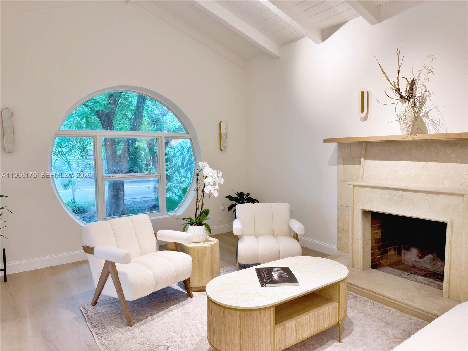 A living room features a circular window, a stone fireplace, and two white armchairs — 775 NE 76th St, Miami FL 33138, MIAMI, FL