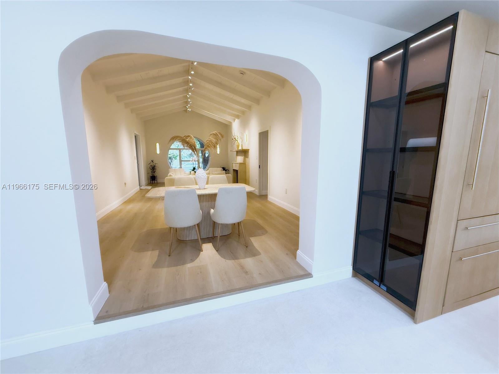 A dining room with a vaulted ceiling and arched entryway connects to a living area — 775 NE 76th St, Miami FL 33138, MIAMI, FL