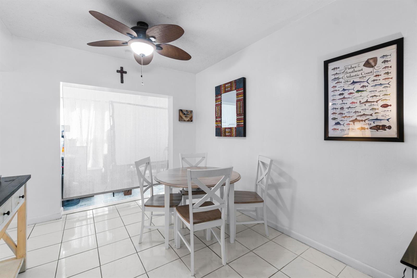 A dining area features a round wooden table, four chairs, tiled floors, and wall decor — 658 NE 6th Court E, Boynton Beach FL 33435, BOYNTON BEACH, FL