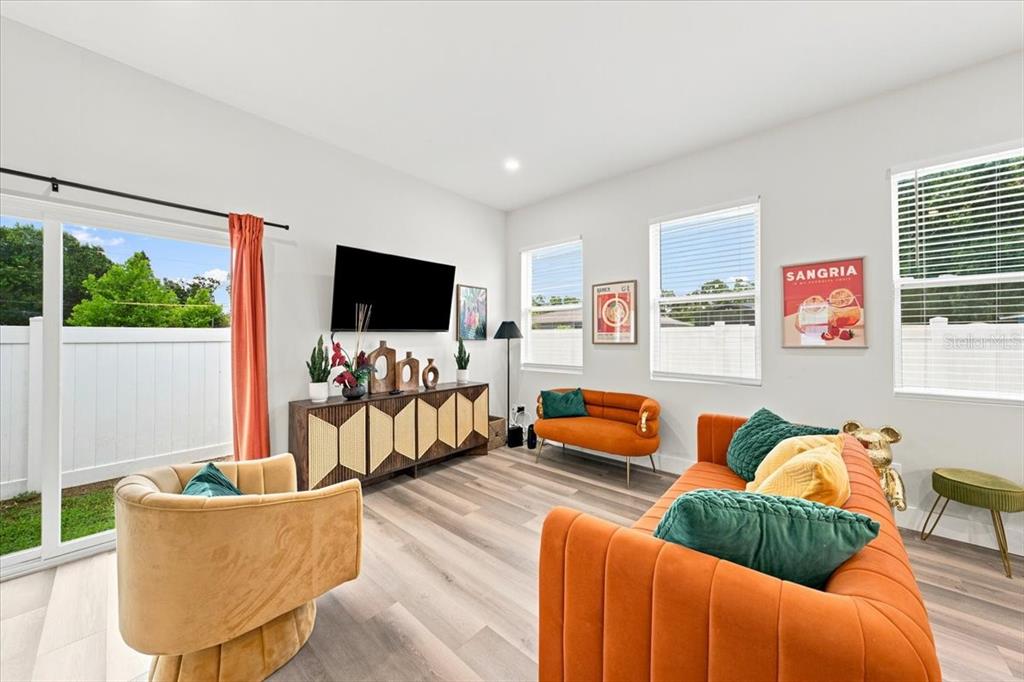 A living room features orange velvet seating, a wooden media console, and light wood flooring — 4390 44TH STREET N, ST PETERSBURG, FL