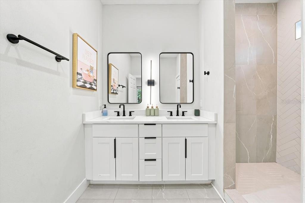 A bathroom features a white double vanity with black hardware, two mirrors, and a shower — 4390 44TH STREET N, ST PETERSBURG, FL