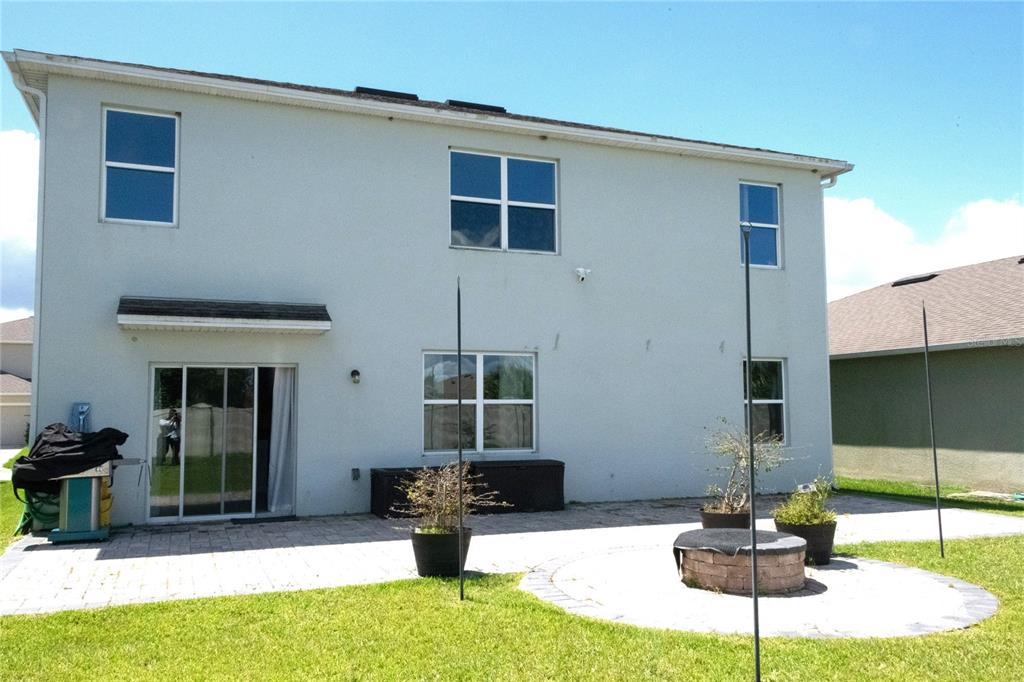 The rear exterior of a two-story house features a paved patio and a fire pit — 3940 SILVERSTREAM TERRACE, SANFORD, FL
