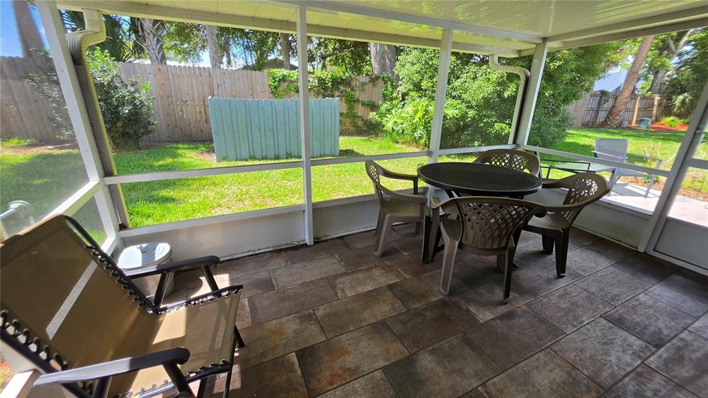 A screened-in patio features tiled flooring, a round dining table with chairs, and backyard views — 4 BIRDIE DRIVE, NEW SMYRNA BEACH, FL