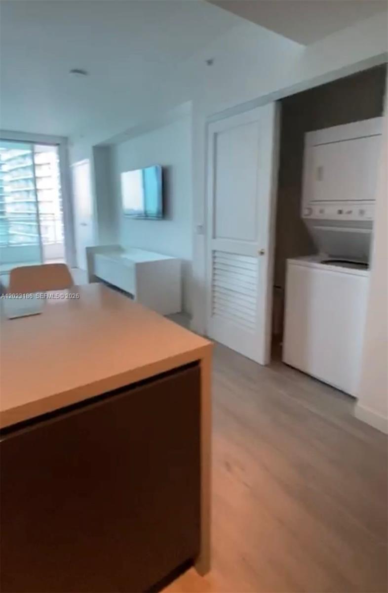 This interior view shows a kitchen island, a living area with a television, and a laundry closet — 1080 Brickell Ave # 2405, Miami FL 33131, MIAMI, FL