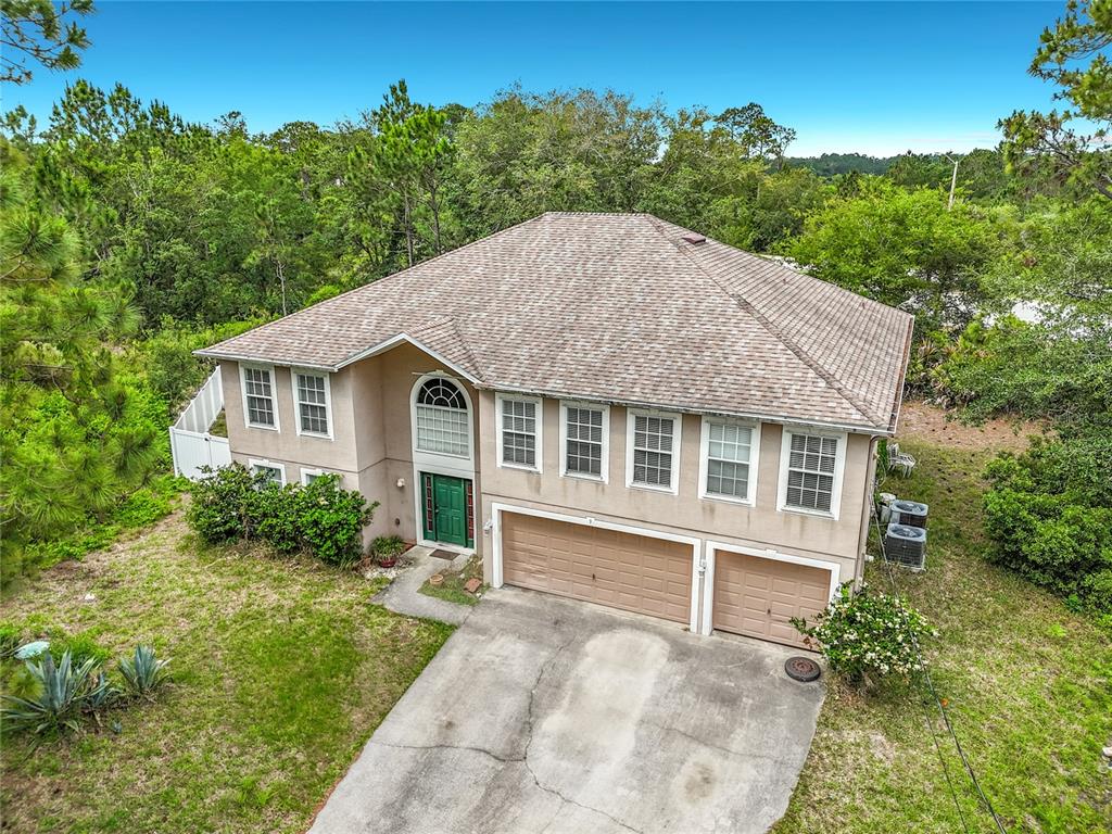 An aerial view of a two-story house with a tan stucco exterior and a shingled roof — 9 BURNE PLACE, PALM COAST, FL