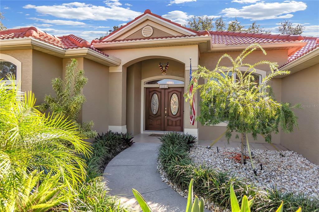 The exterior of a house features a tiled roof, a covered entryway, and landscaping — 5723 EASTWIND DRIVE, SARASOTA, FL