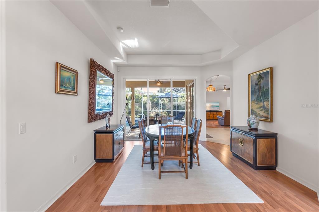 A dining room with a wooden table, chairs, two sideboards, and a sliding glass door — 5723 EASTWIND DRIVE, SARASOTA, FL