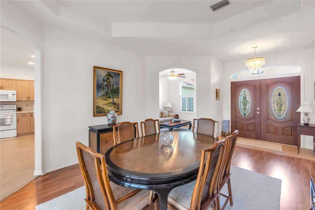 A dining room features a wooden table, cane-back chairs, and an arched entryway to another room — 5723 EASTWIND DRIVE, SARASOTA, FL