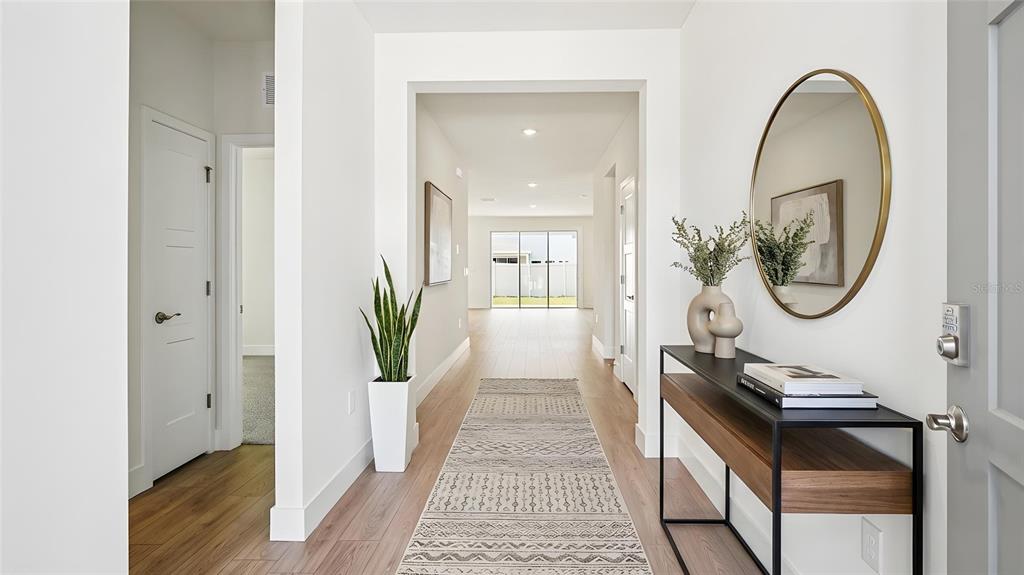 A bright entryway features light wood flooring, a console table, a mirror, and a long hallway — 4241 SW 52ND LANE ROAD, OCALA, FL