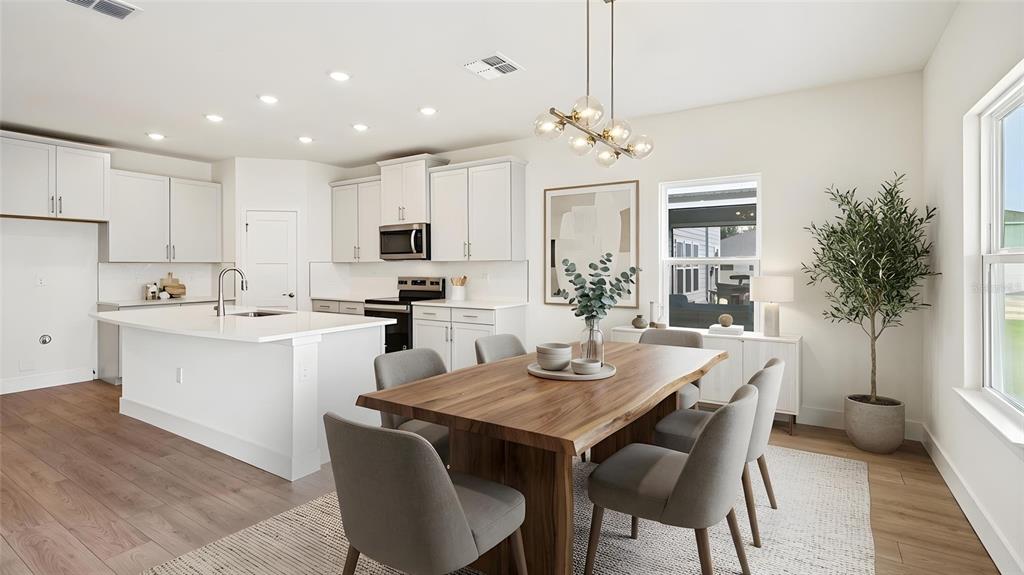 A modern kitchen and dining area features white cabinetry, a wood table, and gray chairs — 4241 SW 52ND LANE ROAD, OCALA, FL