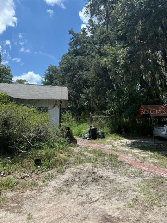 A side view of a house exterior with a brick walkway and a covered carport area — 4543 COBB ROAD, LAND O LAKES, FL