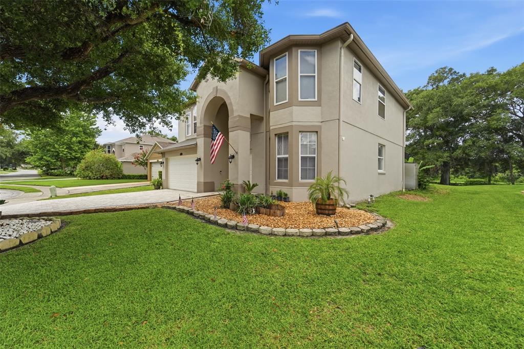 A two-story beige house with a stone-bordered garden bed and a paved driveway — 414 MOHAVE TERRACE, LAKE MARY, FL