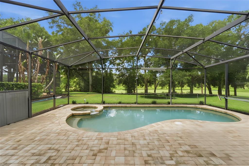 A screened-in pool and spa area with a paver patio overlooking a grassy backyard — 414 MOHAVE TERRACE, LAKE MARY, FL