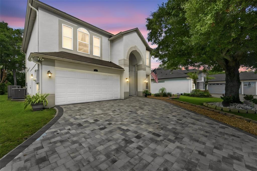 A two-story house with a paved driveway, white garage door, and arched entryway at dusk — 414 MOHAVE TERRACE, LAKE MARY, FL