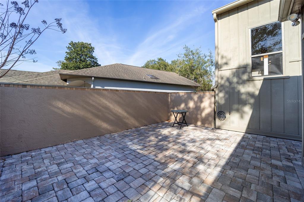 A paved patio area is enclosed by a tan stucco wall next to a house — 1906 SE CLATTERBRIDGE ROAD SE, OCALA, FL