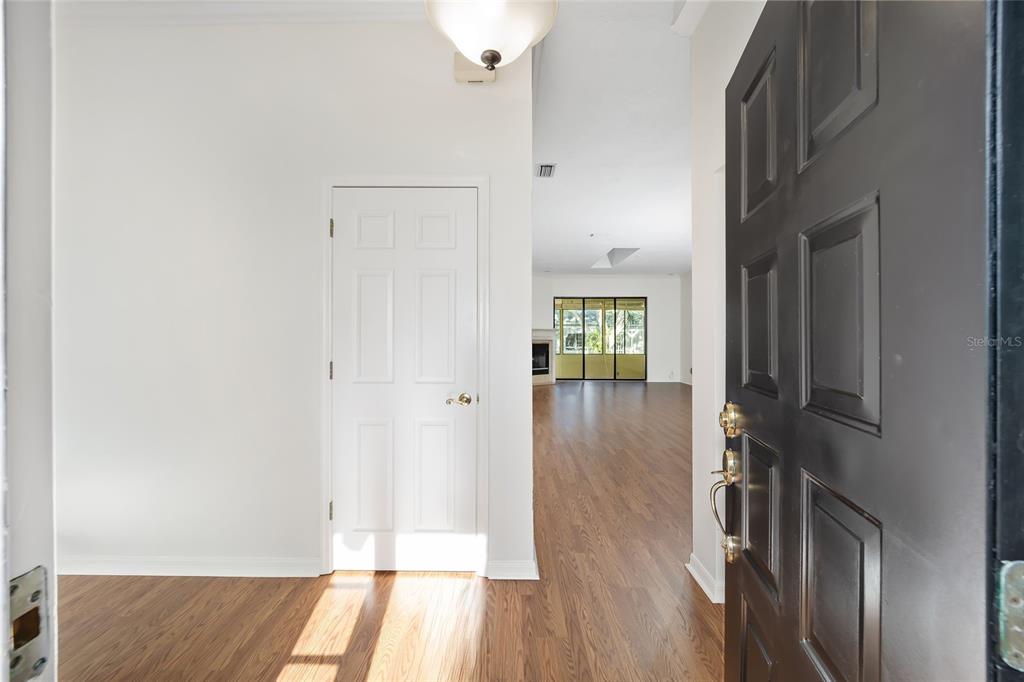 An entryway with wood-look flooring leads into a living area with a fireplace and windows — 1906 SE CLATTERBRIDGE ROAD SE, OCALA, FL
