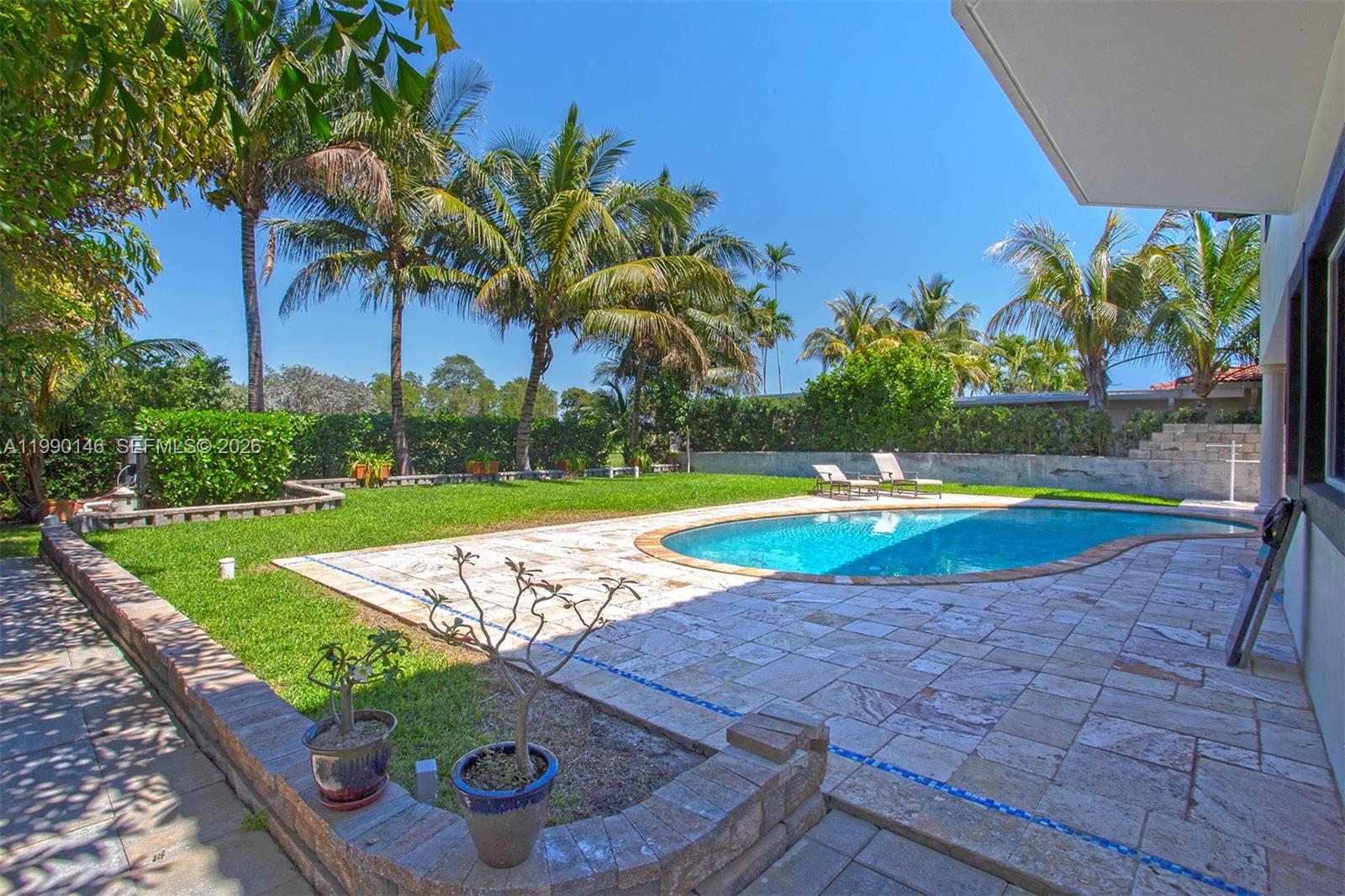 A patio with a swimming pool, outdoor seating, and palm trees under a clear sky — 545 S Shore Dr, Miami Beach FL 33141, MIAMI BEACH, FL