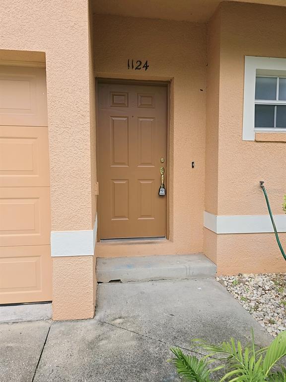 The exterior of a peach-colored home features a brown front door and a garage — 1124 N FAIRWAY DRIVE, APOPKA, FL