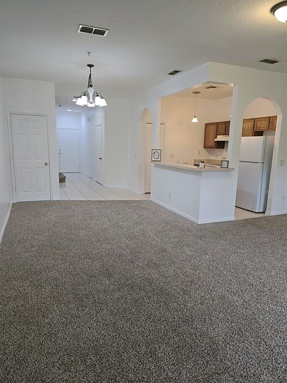 A living room with gray carpet leads to a kitchen with white cabinets and appliances — 1124 N FAIRWAY DRIVE, APOPKA, FL