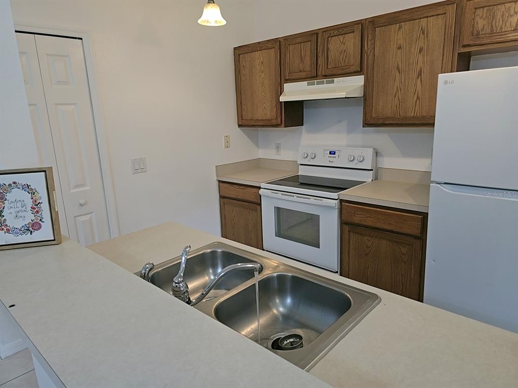 A kitchen features wood cabinets, white appliances, a double-basin sink, and light-colored countertops — 1124 N FAIRWAY DRIVE, APOPKA, FL