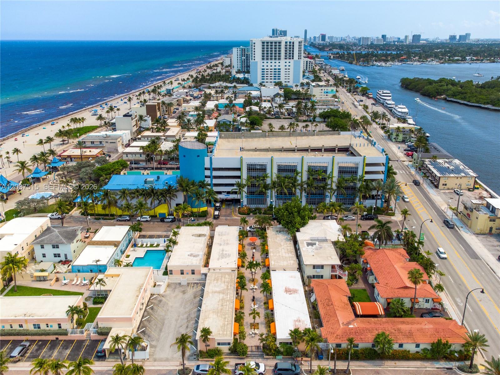 An aerial view shows a coastal neighborhood with a parking garage, beach, and waterway — 336 Arthur St # 118, Hollywood FL 33019, HOLLYWOOD, FL