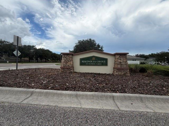 A stone-accented entrance sign for Magnolia Grove at Dupree Lakes sits in a landscaped bed — 6057 SWEET WILLIAM TERRACE, LAND O LAKES, FL