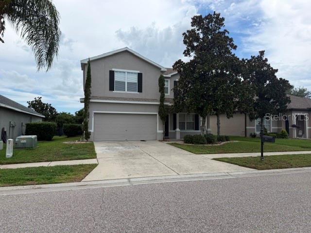 A two-story suburban house with a gray exterior, a two-car garage, and mature trees — 6057 SWEET WILLIAM TERRACE, LAND O LAKES, FL