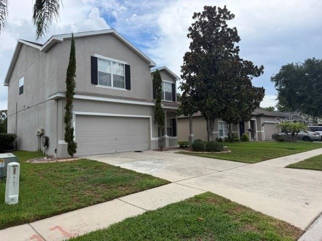 A two-story suburban house with a beige stucco exterior and a two-car garage — 6057 SWEET WILLIAM TERRACE, LAND O LAKES, FL