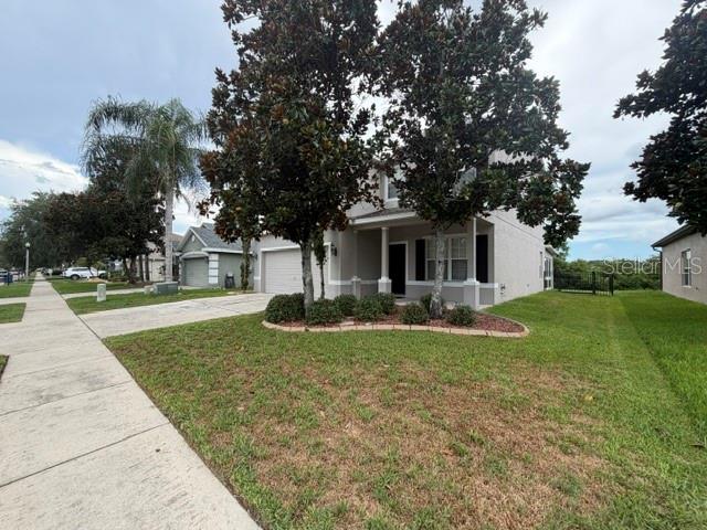A two-story suburban house with a light-colored exterior, a front porch, and mature trees — 6057 SWEET WILLIAM TERRACE, LAND O LAKES, FL