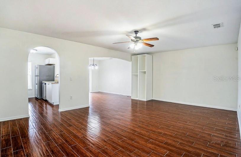 A living room with wood-look tile flooring, a ceiling fan, and an arched kitchen entryway — 9836 ASHBURN LAKE DRIVE, TAMPA, FL