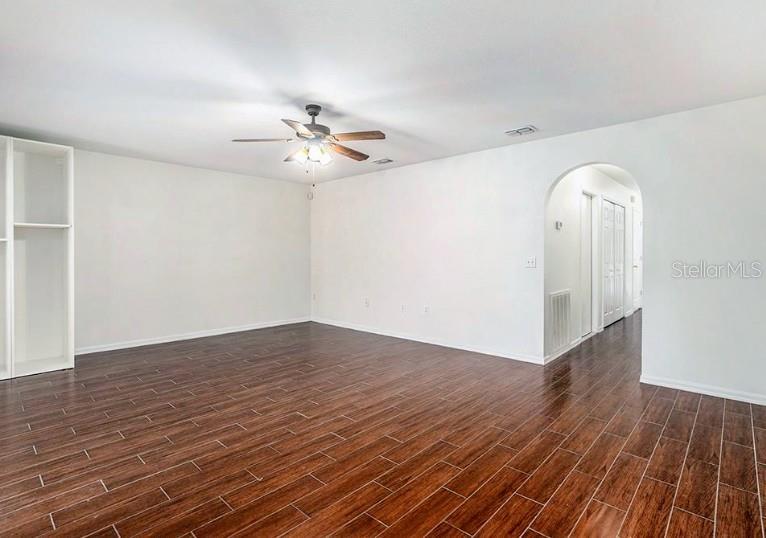 An empty room features dark wood-look tile flooring, white walls, and a ceiling fan — 9836 ASHBURN LAKE DRIVE, TAMPA, FL