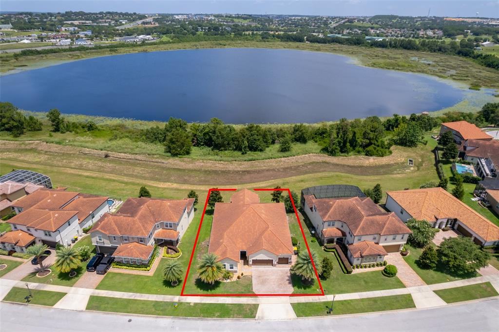 An aerial view shows a single-family home with a tile roof facing a large lake — 3546 MEDITERRA DRIVE, CLERMONT, FL