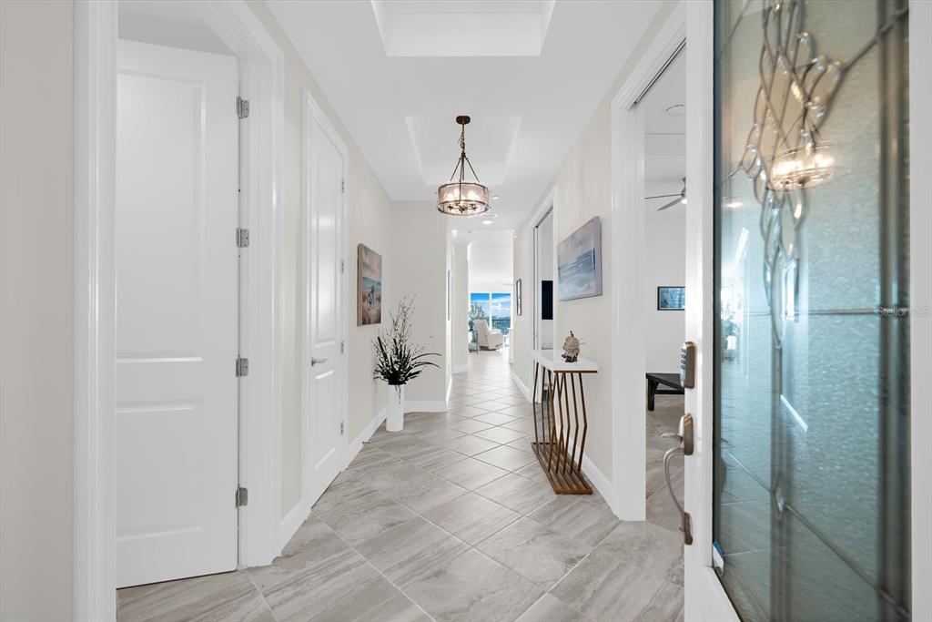 A bright hallway features light-colored tile flooring, white doors, and a decorative ceiling light fixture — 507 TAMIAMI TRAIL N UNIT 602, VENICE, FL