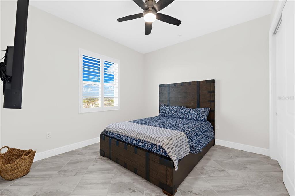 A bedroom features a dark wood bed frame, tile flooring, and a ceiling fan — 507 TAMIAMI TRAIL N UNIT 602, VENICE, FL