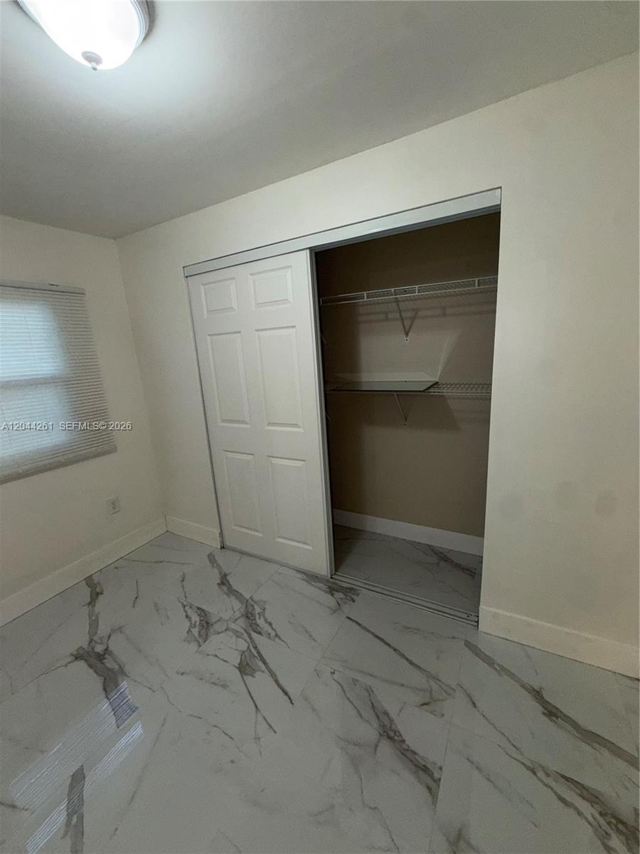 A bedroom features white walls, a sliding closet door, and white marble-patterned tile flooring — 6497 W 8th Ln # 6497, Hialeah FL 33012, HIALEAH, FL
