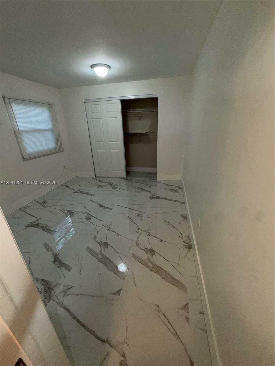 A bedroom features white walls, a sliding closet door, and polished white marble-patterned tile flooring — 6497 W 8th Ln # 6497, Hialeah FL 33012, HIALEAH, FL