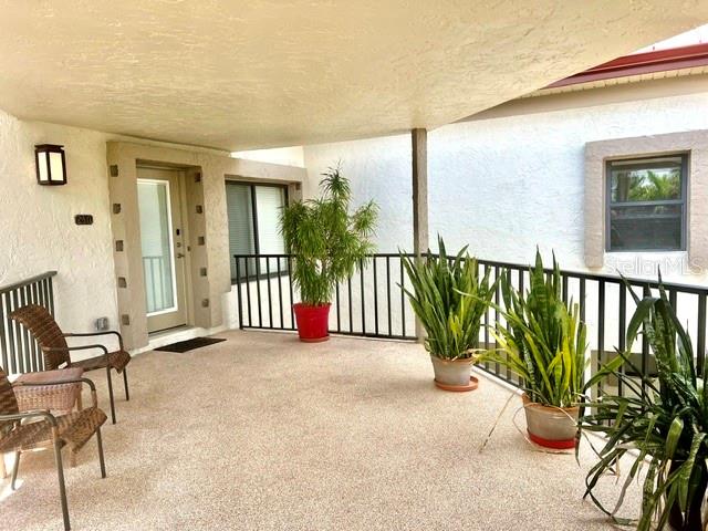 A covered outdoor patio features a textured floor, potted plants, and a glass-paneled entry door — 3220 SOUTHSHORE DRIVE UNIT 23C, PUNTA GORDA, FL