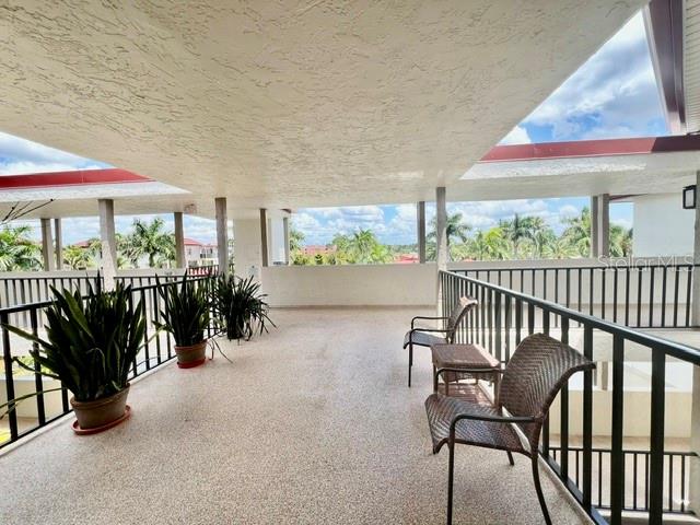 A covered outdoor balcony features a textured floor, potted plants, and two wicker chairs — 3220 SOUTHSHORE DRIVE UNIT 23C, PUNTA GORDA, FL