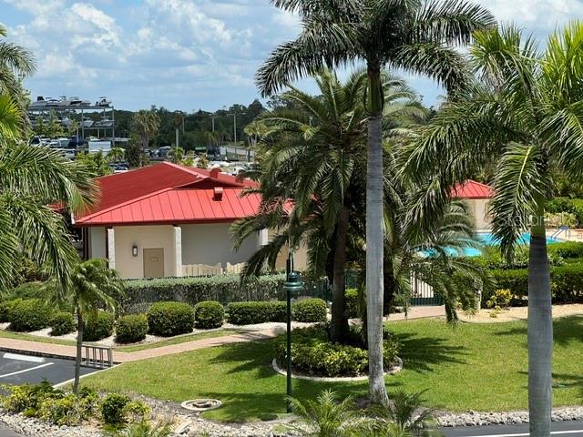 A red-roofed building sits in a landscaped area with palm trees and a swimming pool — 3220 SOUTHSHORE DRIVE UNIT 23C, PUNTA GORDA, FL