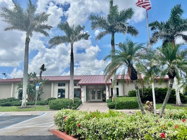 A single-story building with a red metal roof is surrounded by tall palm trees — 3220 SOUTHSHORE DRIVE UNIT 23C, PUNTA GORDA, FL