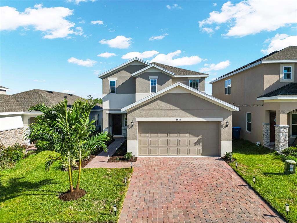 A two-story suburban house with a paved driveway, a two-car garage, and exterior landscape lighting — 1601 SWAN SWIM DRIVE, DAVENPORT, FL