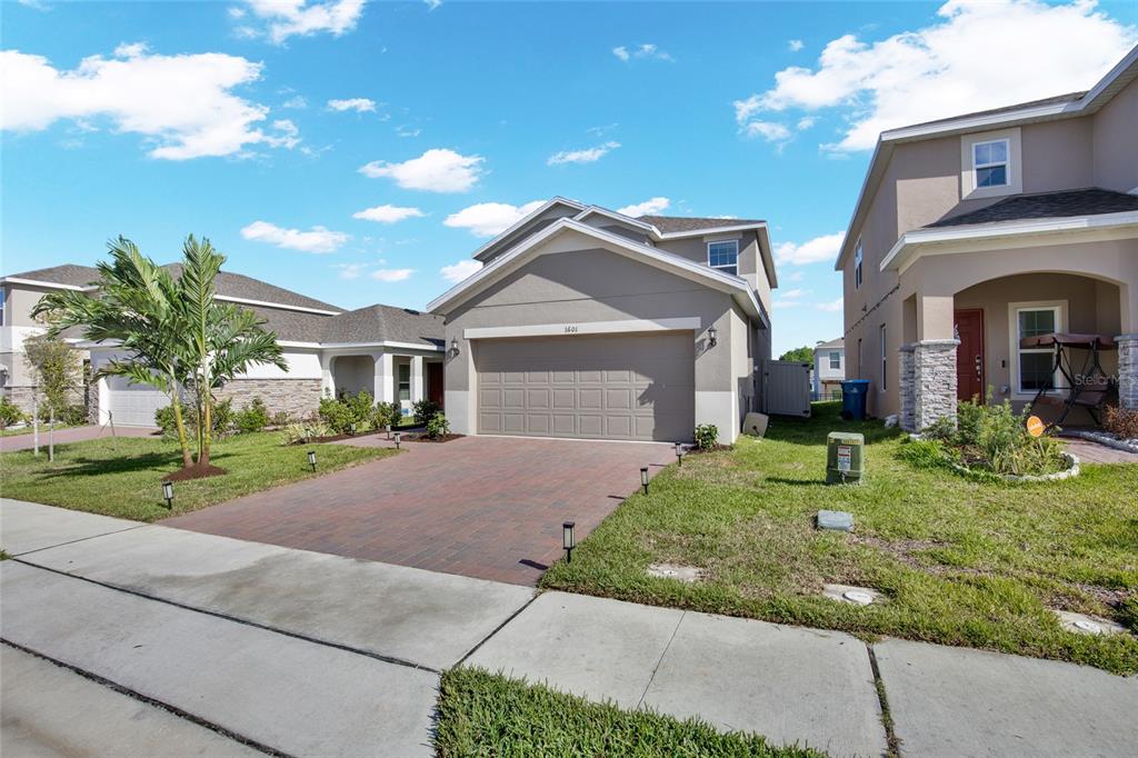 A two-story suburban house with a paved driveway, a two-car garage, and a front lawn — 1601 SWAN SWIM DRIVE, DAVENPORT, FL